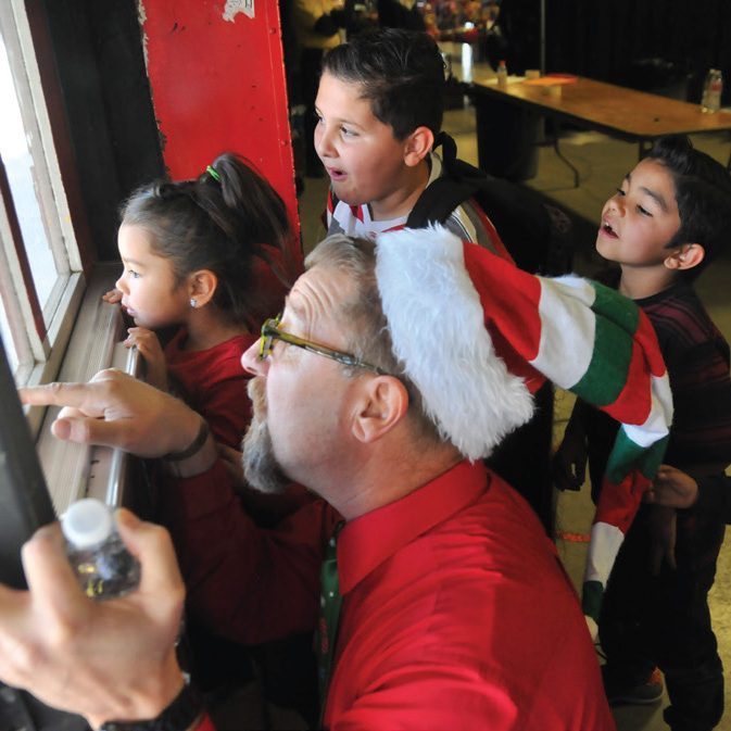 Director Bill Edwards plays Santa and anticipates gifts with children at the Mission’s event last year.