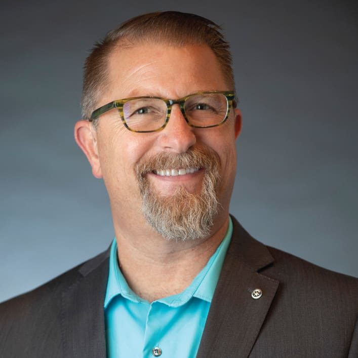 Smiling middle-aged man with glasses, a mustache, and goatee—Jeremy wears a teal shirt and dark blazer, posed in front of a plain gradient background, ready to reclaim his future with faith in God.